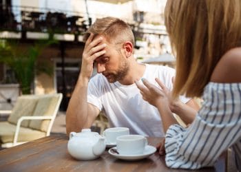 Young beautiful couple drinking tea, speaking, quarreling, sitting in cafe