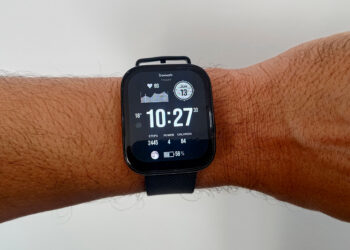 O smartwatch Amazfit Bip 5 Pro visto de perto no pulso, destacando seu design quadrado e a tela LCD exibindo o mostrador principal com horas e dados de atividade física.