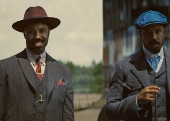Cena do filme Pecadores (2025) mostrando os irmãos interpretados por Michael B. Jordan com trajes de época dos anos 1930.