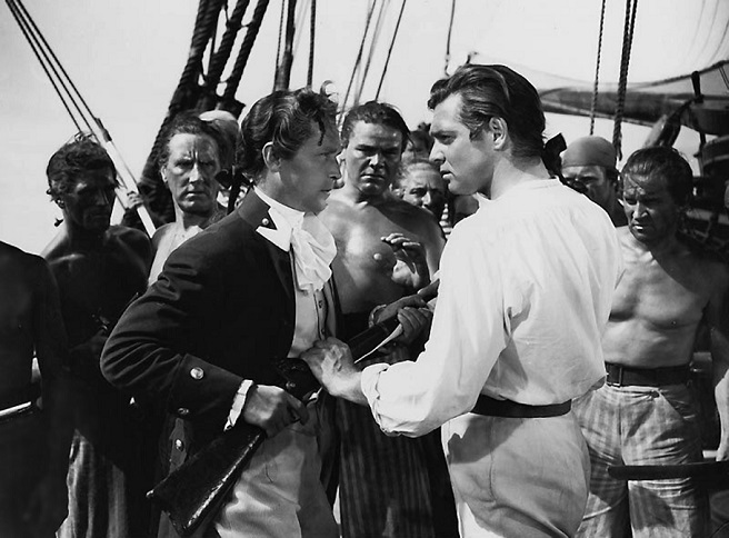 Cena do motim no filme O Grande Motim (1935), com Fletcher Christian (Clark Gable) confrontando o Capitão Bligh (Charles Laughton) no convés do navio.