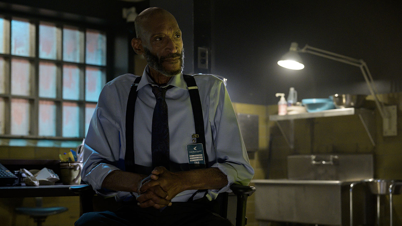 O ator Tony Todd como o personagem William Bludworth no filme Premonição 6, sentado em um necrotério.