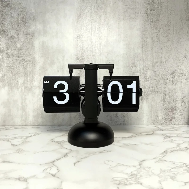 Relógio flip clock preto fosco sobre uma superfície de mármore branco, marcando 3:01 da manhã.