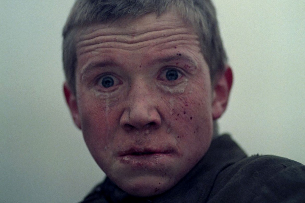 Close-up do rosto traumatizado do jovem Florya, protagonista do filme de guerra Vá e Veja (1985).