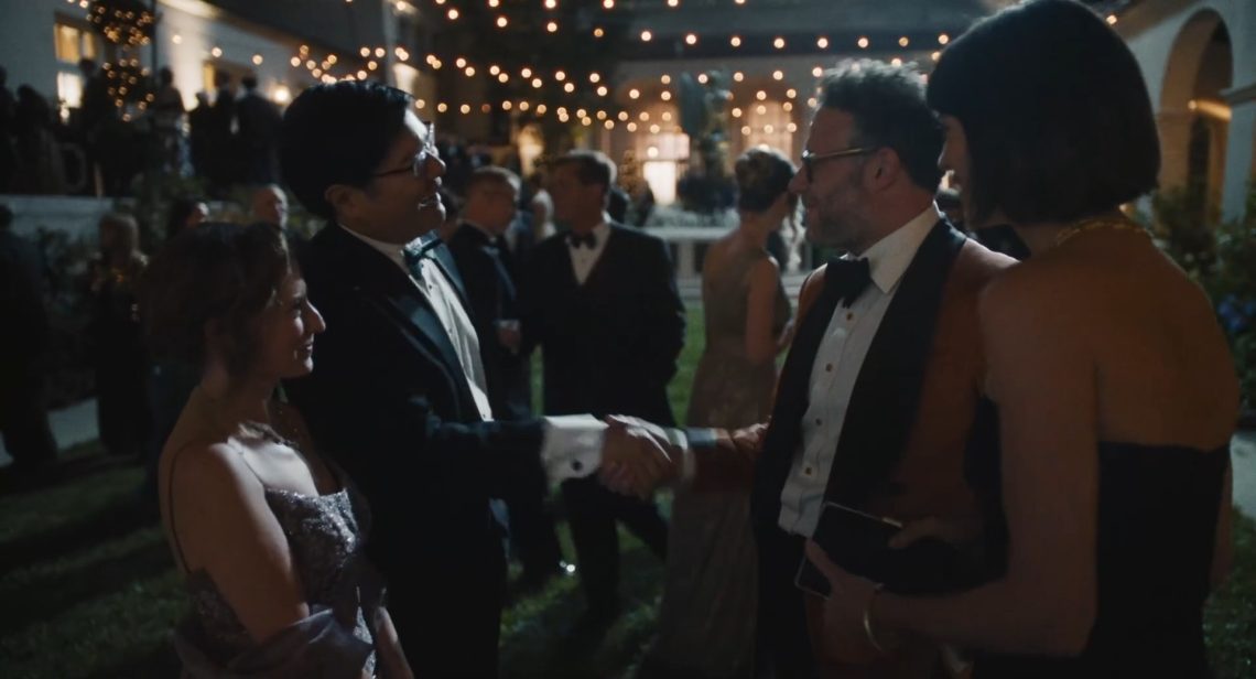 Cena da série O Estúdio: Matt Remick (Seth Rogen), vestindo um terno marrom, cumprimenta um homem de smoking em uma festa de gala.