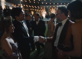 Cena da série O Estúdio: Matt Remick (Seth Rogen), vestindo um terno marrom, cumprimenta um homem de smoking em uma festa de gala.