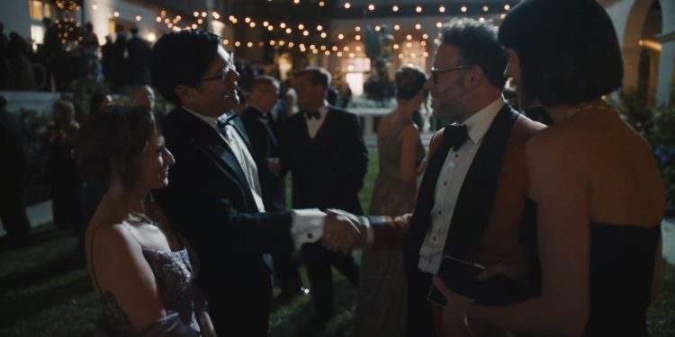 Cena da série O Estúdio: Matt Remick (Seth Rogen), vestindo um terno marrom, cumprimenta um homem de smoking em uma festa de gala.