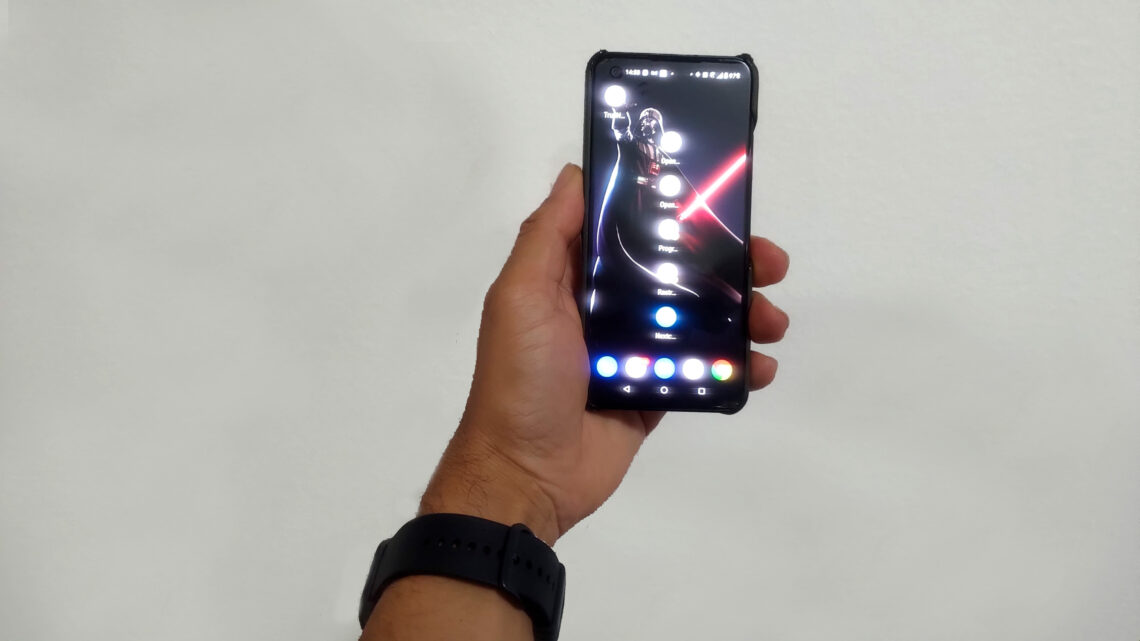 Mão de um homem segurando um smartphone Asus Zenfone 9 preto, demonstrando seu tamanho compacto e usabilidade com uma mão.
