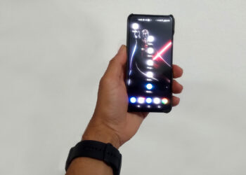 Mão de um homem segurando um smartphone Asus Zenfone 9 preto, demonstrando seu tamanho compacto e usabilidade com uma mão.
