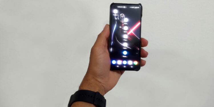 Mão de um homem segurando um smartphone Asus Zenfone 9 preto, demonstrando seu tamanho compacto e usabilidade com uma mão.