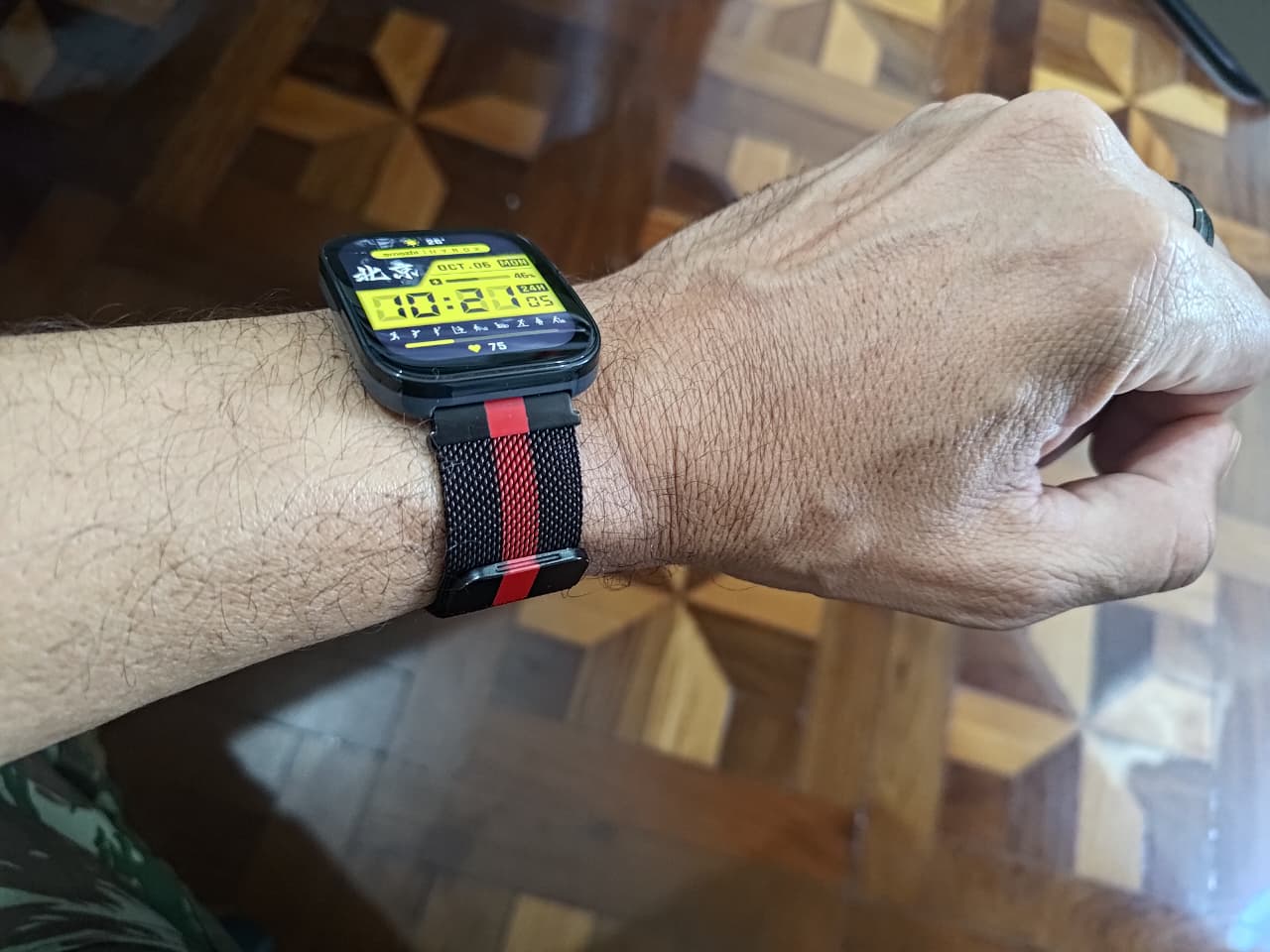 Um relógio Amazfit Bip com uma pulseira preta e vermelha nas cores do Flamengo no pulso de uma pessoa.