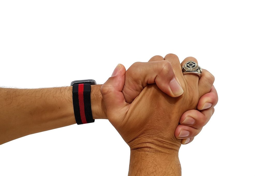 Mãos unidas em gesto de propósito, com relógio e anel.