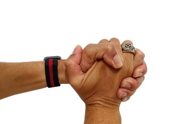 Mãos unidas em gesto de propósito, com relógio e anel.