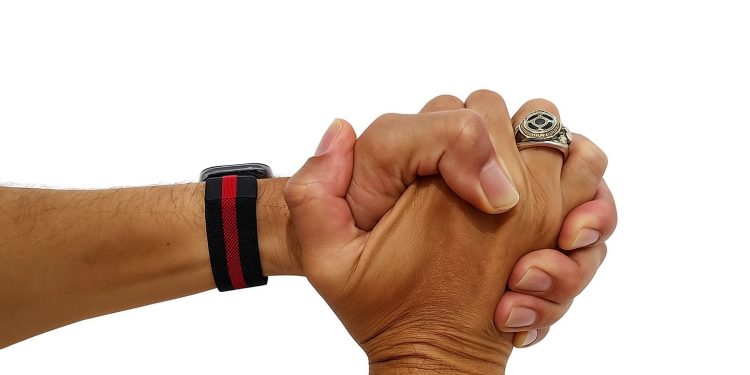 Mãos unidas em gesto de propósito, com relógio e anel.