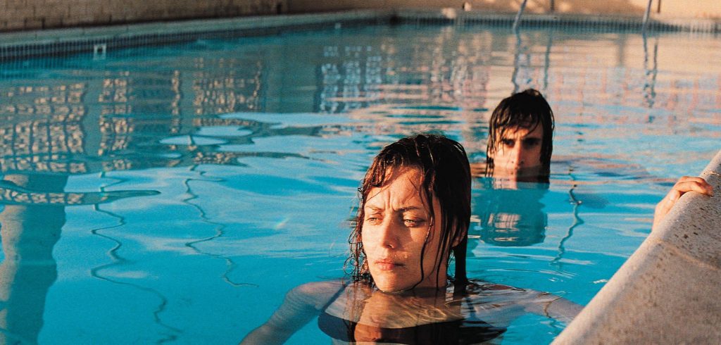 David e Katia, os protagonistas do filme 29 Palms, em uma piscina com expressões de desolação e cansaço.