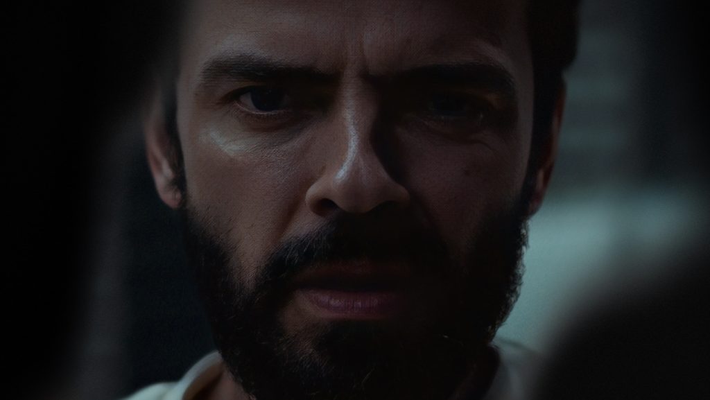 Close-up do rosto de Gleb (Anton Lapenko) no filme Um Homem de Sucesso, com expressão intensa de medo e tensão em ambiente escuro.