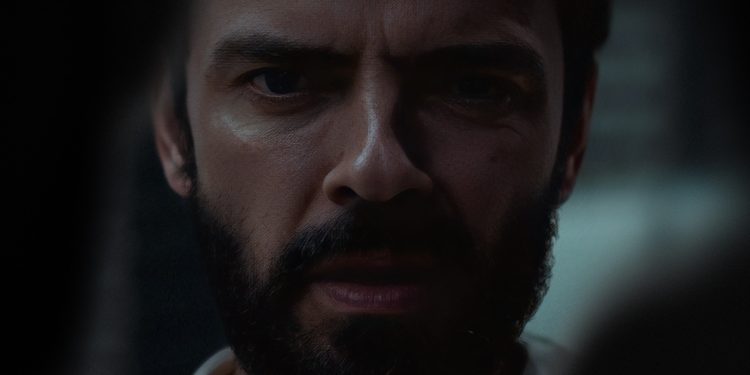 Close-up do rosto de Gleb (Anton Lapenko) no filme Um Homem de Sucesso, com expressão intensa de medo e tensão em ambiente escuro.