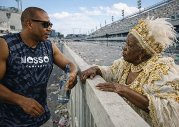 Robert, vestindo o abadá do "Nosso Camarote", conversa com uma senhora da Velha Guarda na beira da pista da Sapucaí.