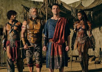 Personagens de Spartacus House of Ashur em trajes de batalha e togas romanas em um cenário de arena rústico.