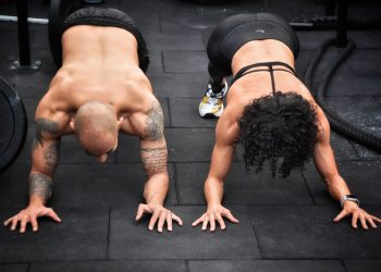 Homem e mulher em posição de prancha no treino de crossfit mostrando a força e a funcionalidade do corpo humano.