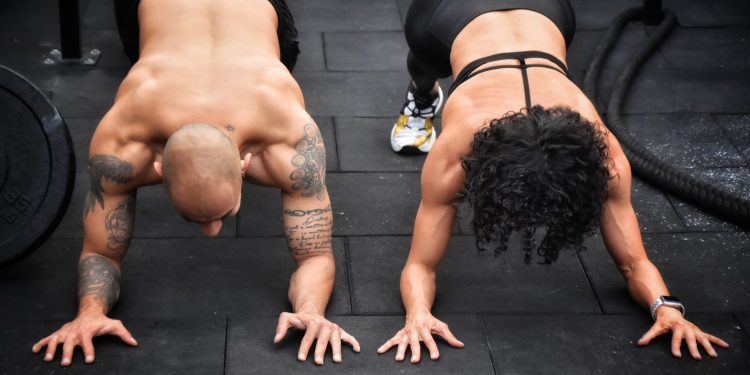 Homem e mulher em posição de prancha no treino de crossfit mostrando a força e a funcionalidade do corpo humano.
