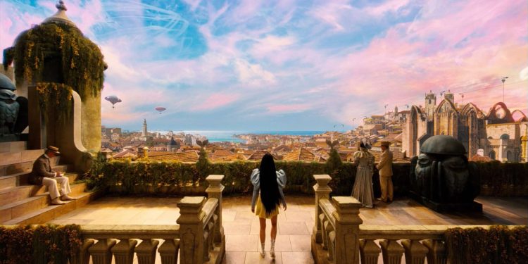 Personagem Bella Baxter de costas, observando uma paisagem surreal e colorida de uma cidade com balões no céu, em uma cena do filme Pobres Criaturas, representando a descoberta e a experimentação do mundo.